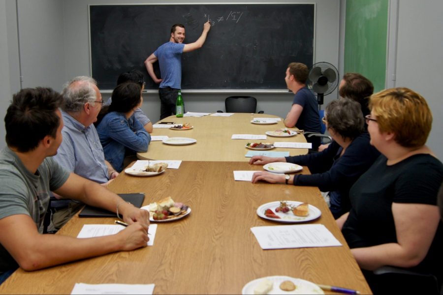 Man at chalkboard in front of conference table