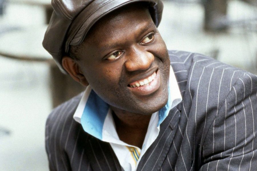 Alain Mabanckou looks away from the camera and smiles in a close-up shot