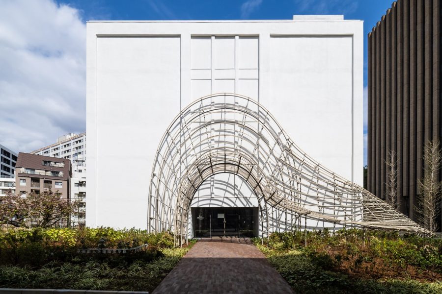 Waseda International House of Literature in Tokyo, an imposing white structure with whimsical curved scaffolding around the entrance, is shown