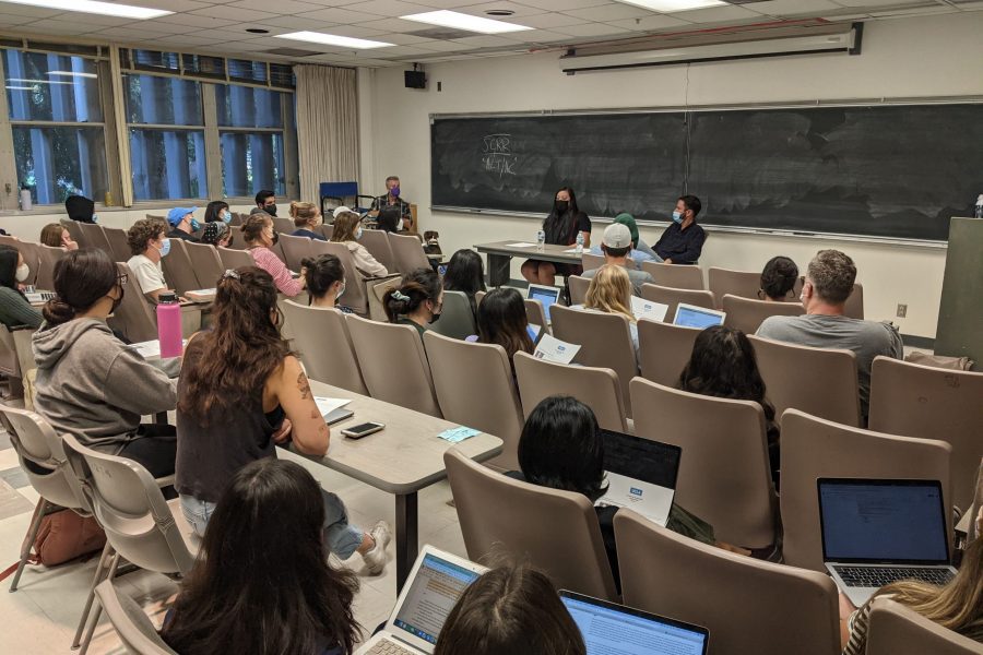 Photo of a classroom from behind. The backs of students' heads are visible.