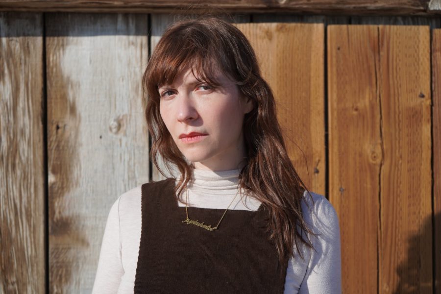 Elaine Kahn stares piercingly at the camera against a wooden plank background