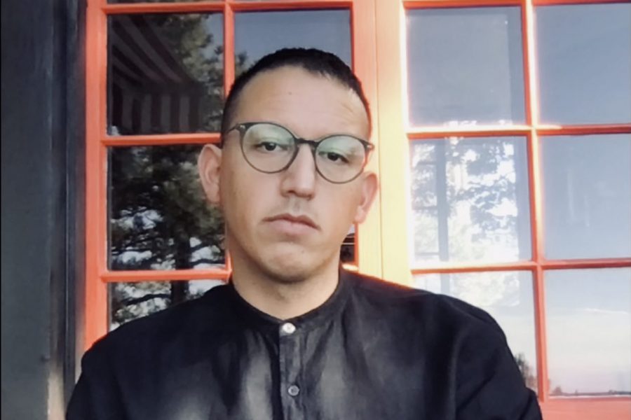 Joshua Javier Guzmán poses against red windowpanes.