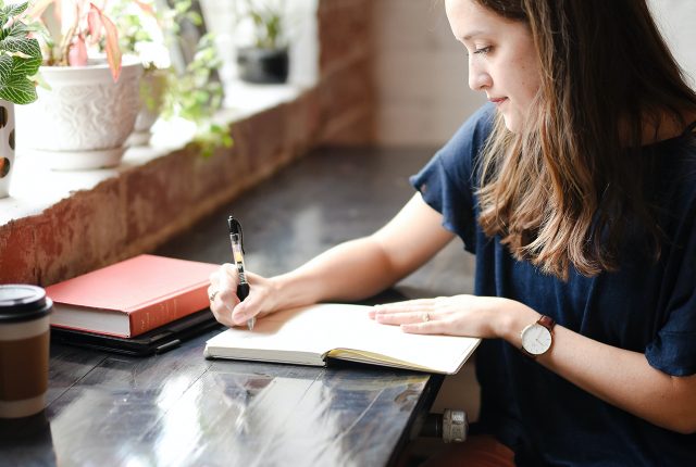 Woman sitting at table writing in notebook