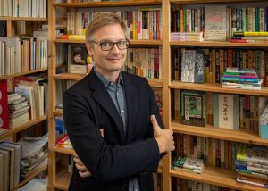 Portrait of UCLA professor Michael Emmerich standing in front of bookshelves