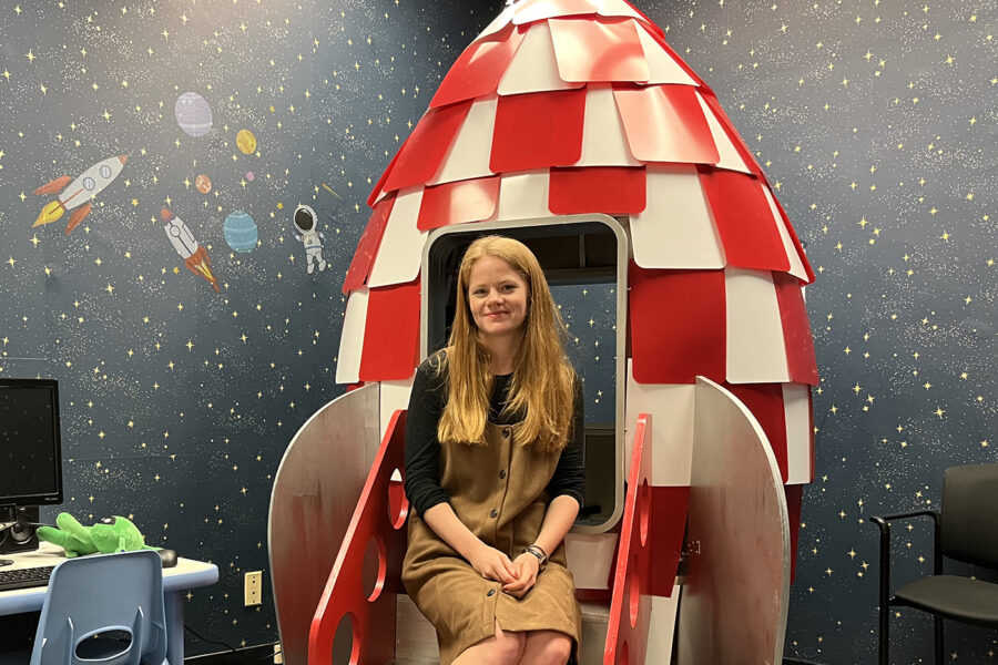 Meg Cychosz sitting in a model rocket ship in her research lab