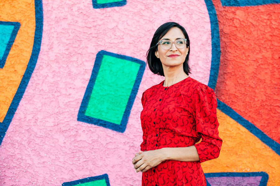 Carribean Fragoza wearing red dress standing in front of brightly colored wall