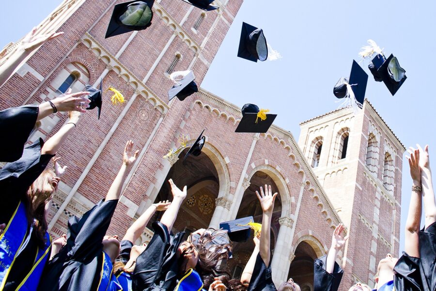 UCLA graduates tossing their caps into the air for commencement with Royce Hall in the background