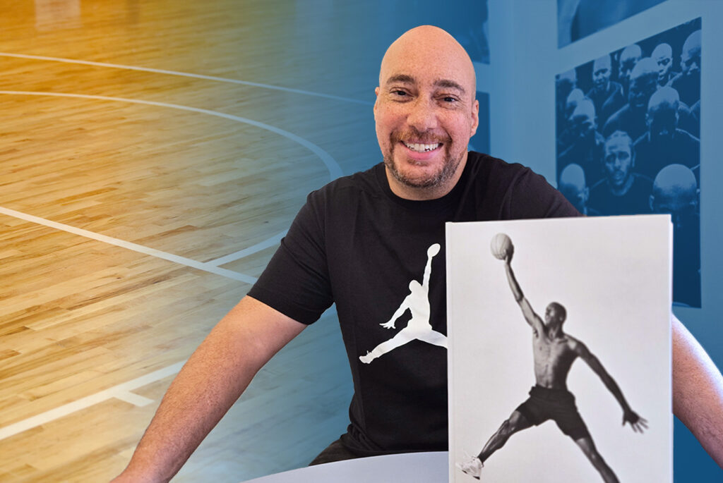 Adam Bradley with Air Jordan book in front of him and basketball court behind him