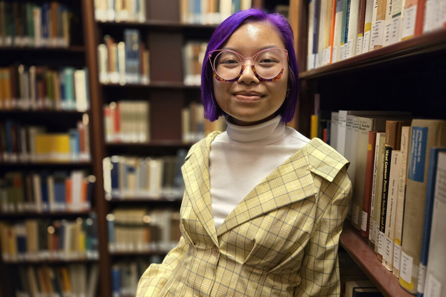 Minh-Thu Nguyen standing next to bookshelves