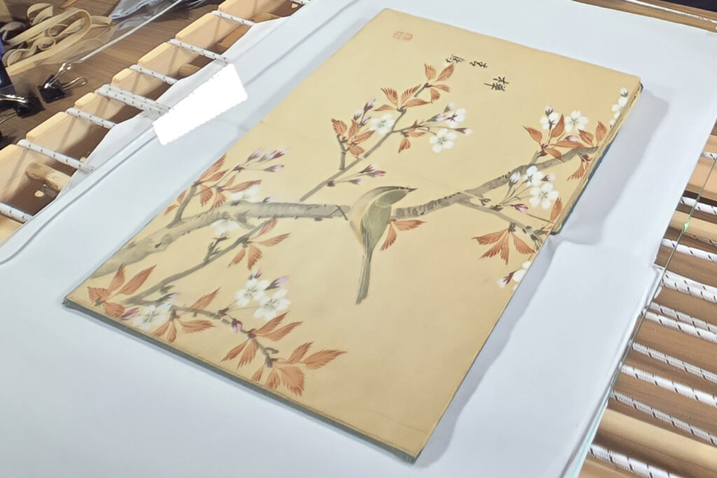 Book on scanner bed, with illustration of bird on flowering tree branch