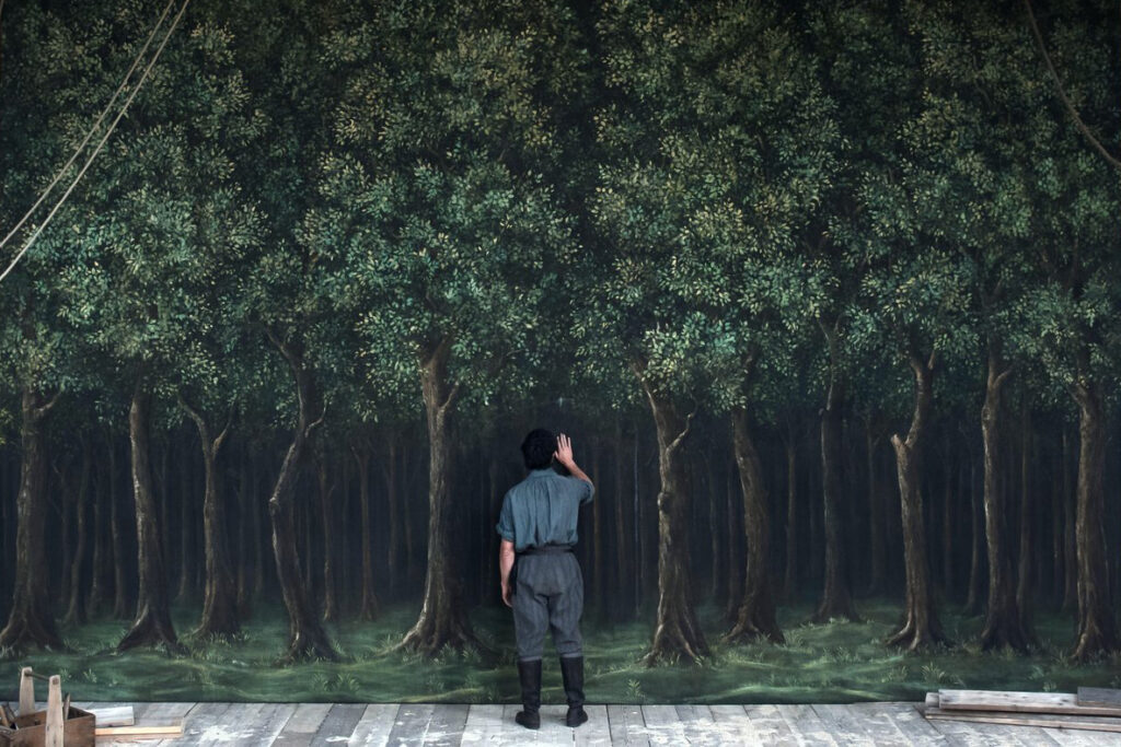 Image from Hamnet movie with Will character looking at backdrop of trees