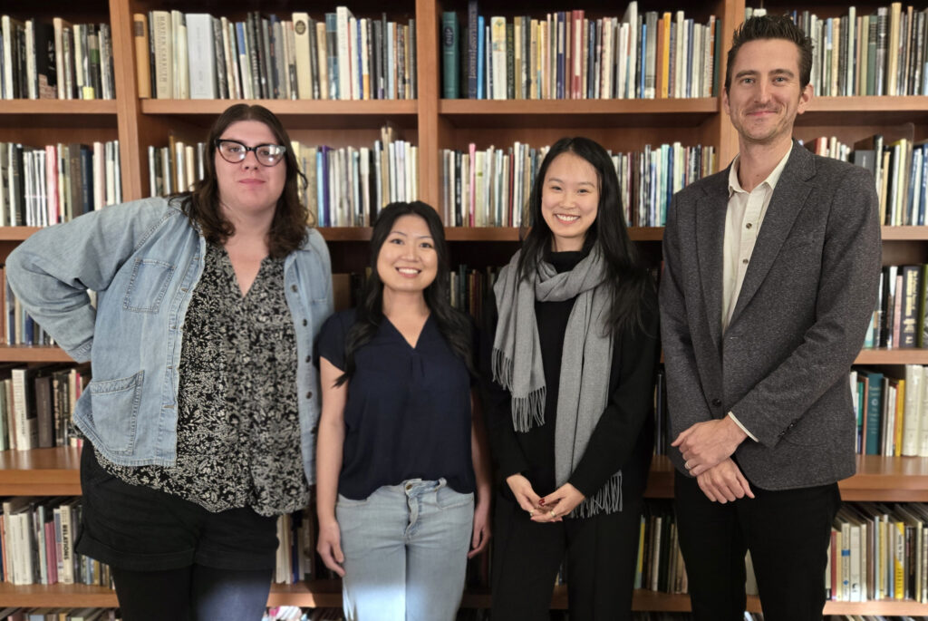 Rosalind Shoopmann, Kim Hu, Sunny Xiaoyang Hua and Alex Mazzaferro posing in front of bookshelf