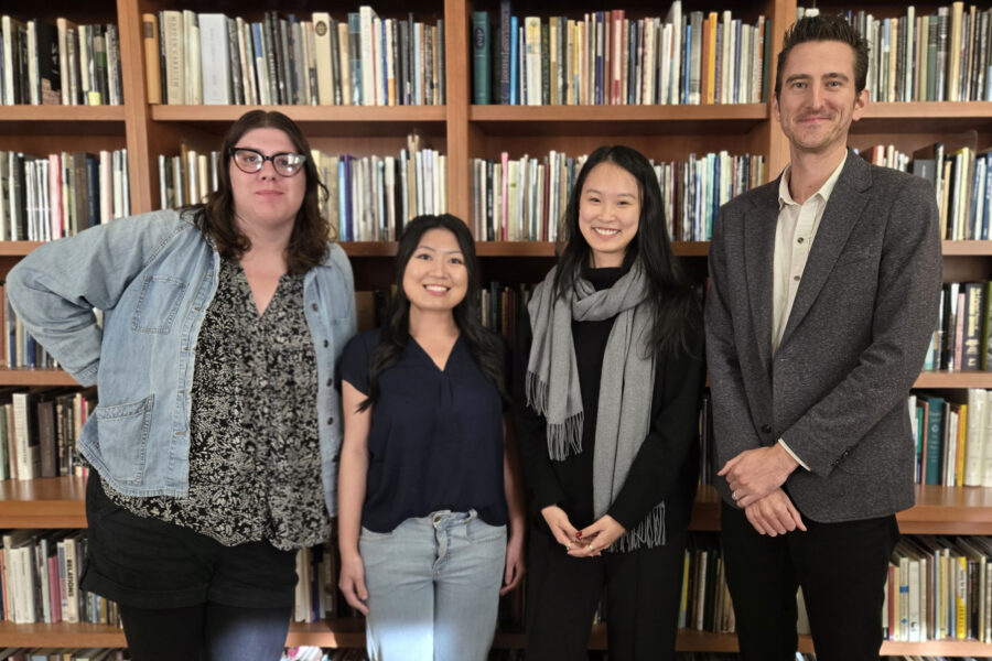 Rosalind Shoopmann, Kim Hu, Sunny Xiaoyang Hua and Alex Mazzaferro posing in front of bookshelf