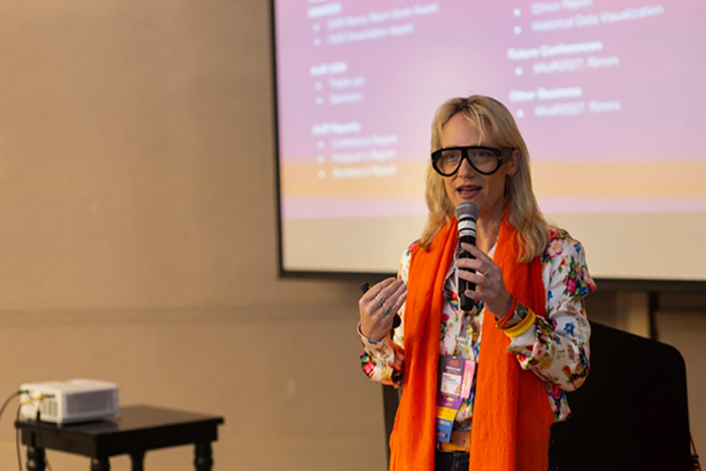Sarah T. Roberts holding a microphone speaking at a conference